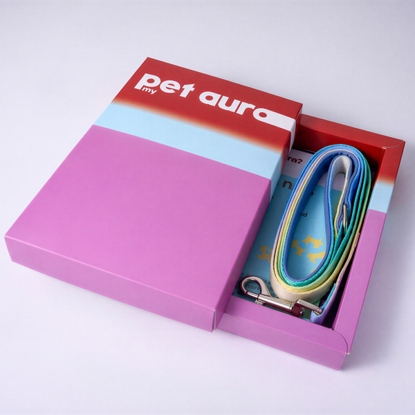 A pet accessory gift set in a colorful box. The set includes a pink and red bag with a white 'pet aura my' logo, a light blue dog leash with yellow and green accents, and a small booklet, all arranged in a pink and red presentation box on a light gray background.